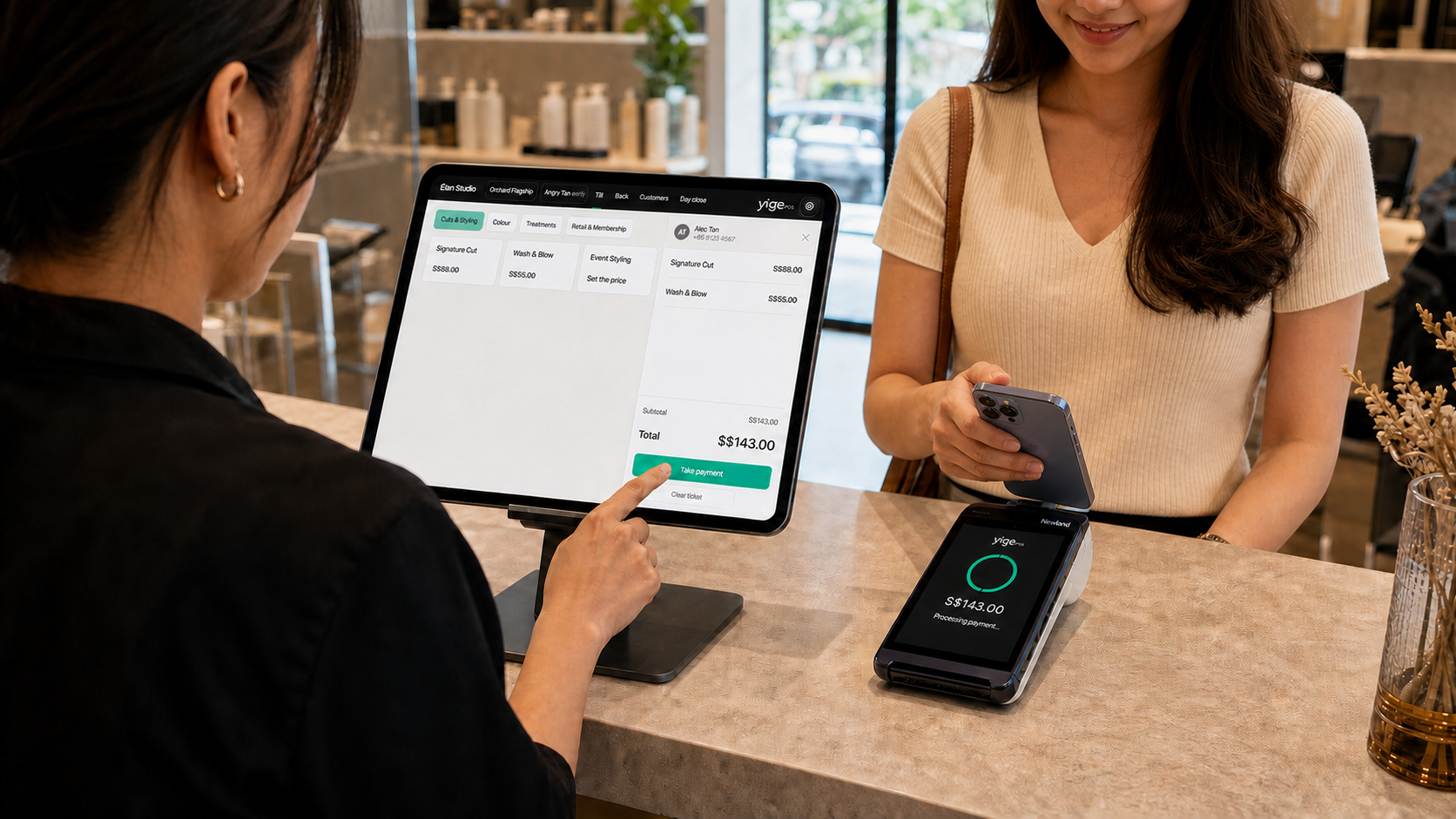 A service-business team using YigePOS on an iPad while a customer completes payment at the counter